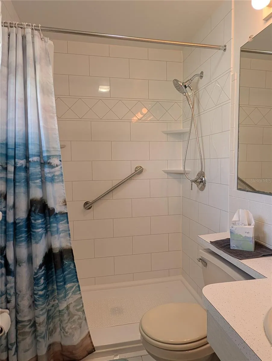 Updated walk-in shower has 2 grab bars, chrome hardware and subway tile surround.