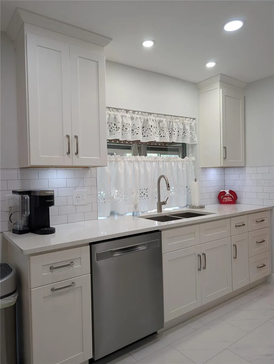 Kitchen window looks into Florida room. Updated kitchen also features gorgeous tile flooring, 36" white shaker wood cabinets w/soft close door/drawer and inset lights (no drop popcorn ceiling).