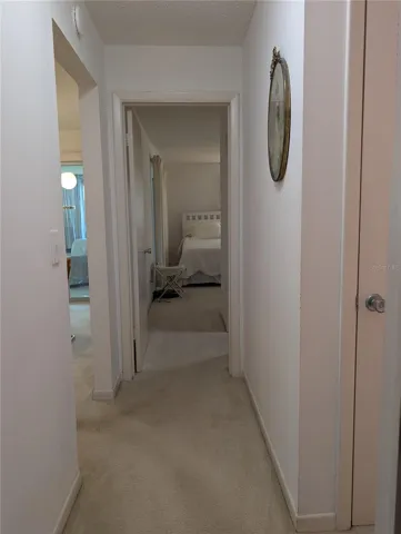 View from guest bedroom down hallway to primary bedroom with ensuite bath.  Linen closet at entry to main bathroom on right.  Living area on left.