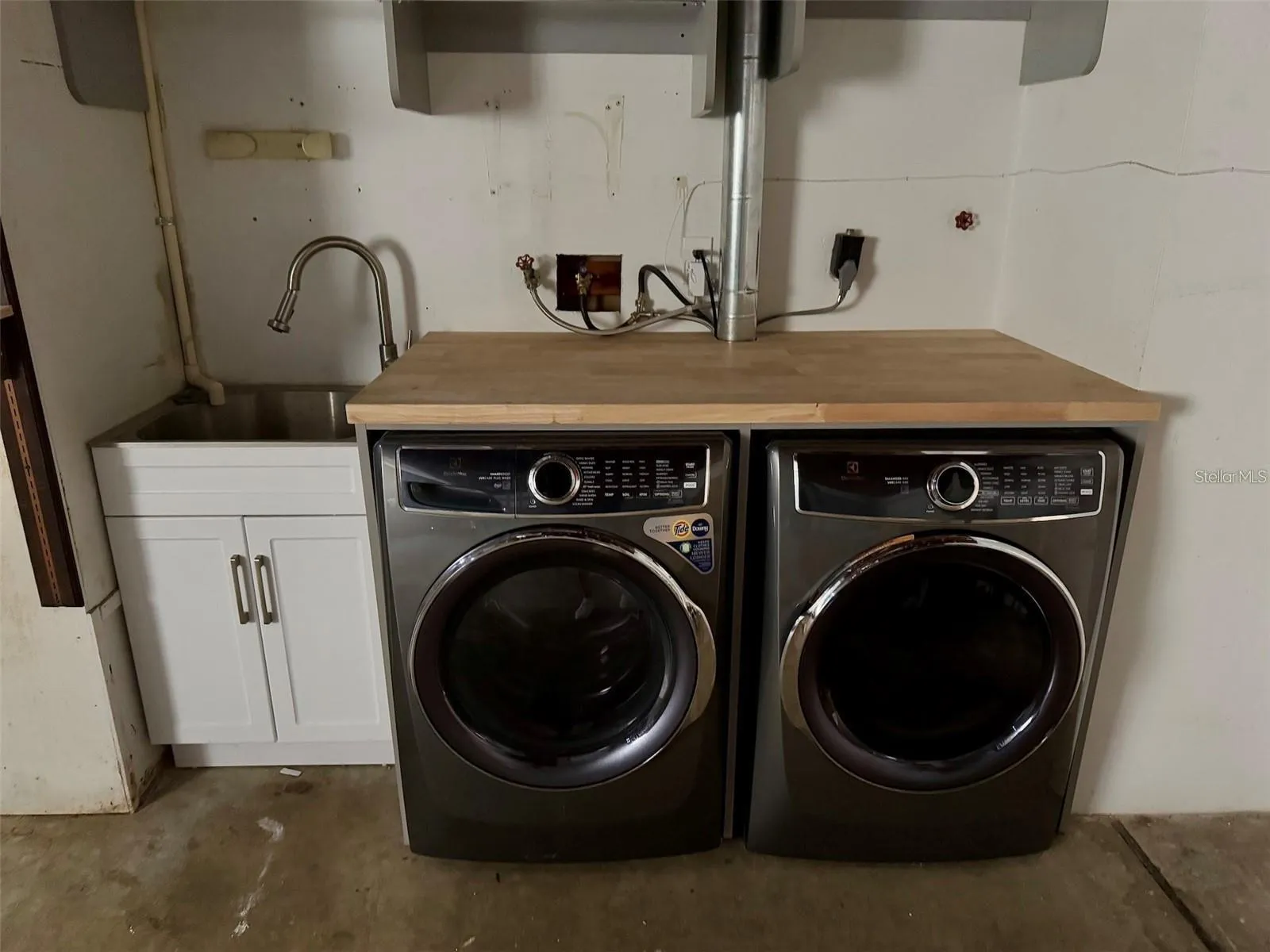 Laundry facilities are located in the garage with a sink and storage.