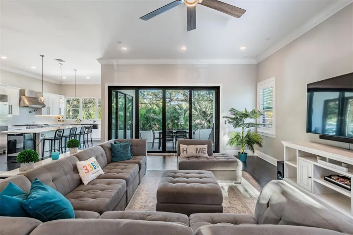 A large great room with crown molding and sliders to the outdoor kitchen and pool deck.