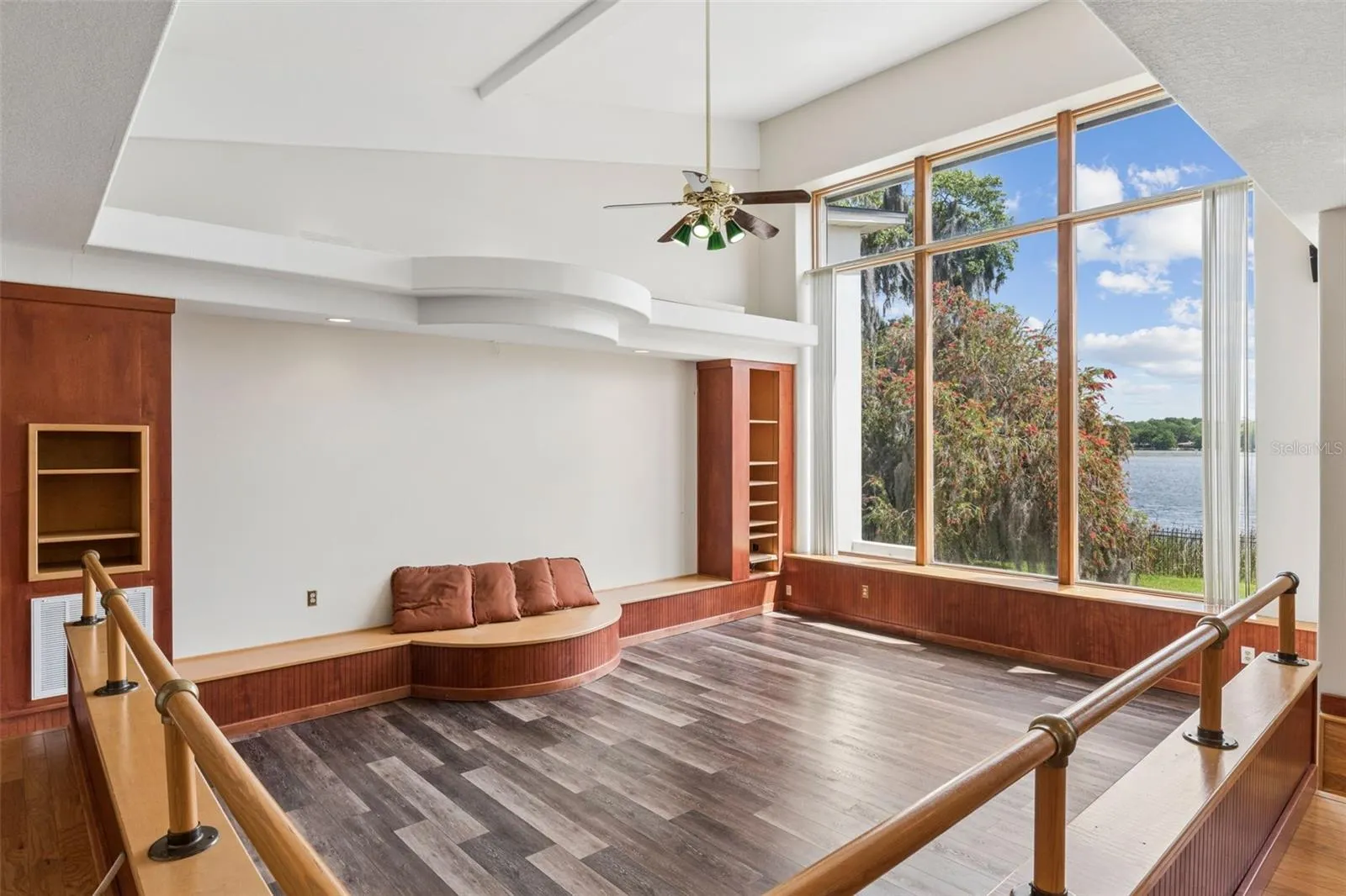 Sunken great room with soaring ceilings, custom built-ins, and floor-to-ceiling windows framing stunning lake views.