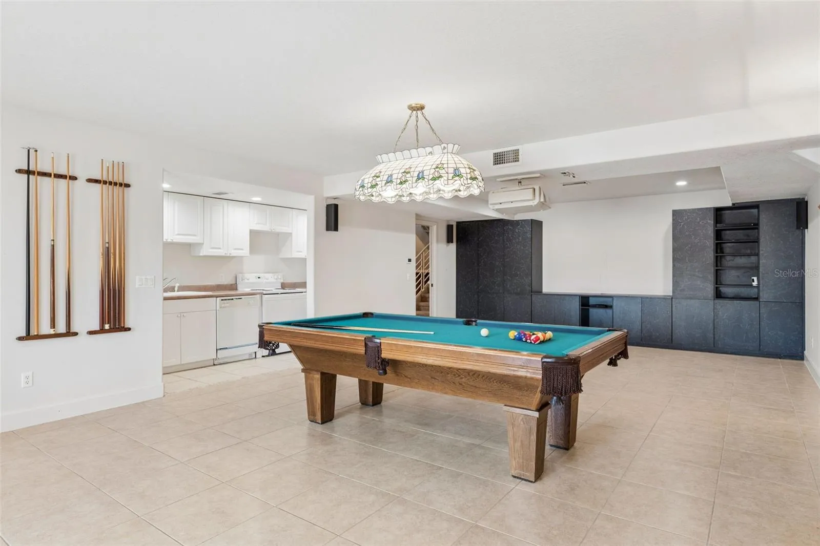 Full-size basement living room with kitchenette, offering separate living quarters with a bedroom and full bath leading to the pool deck.