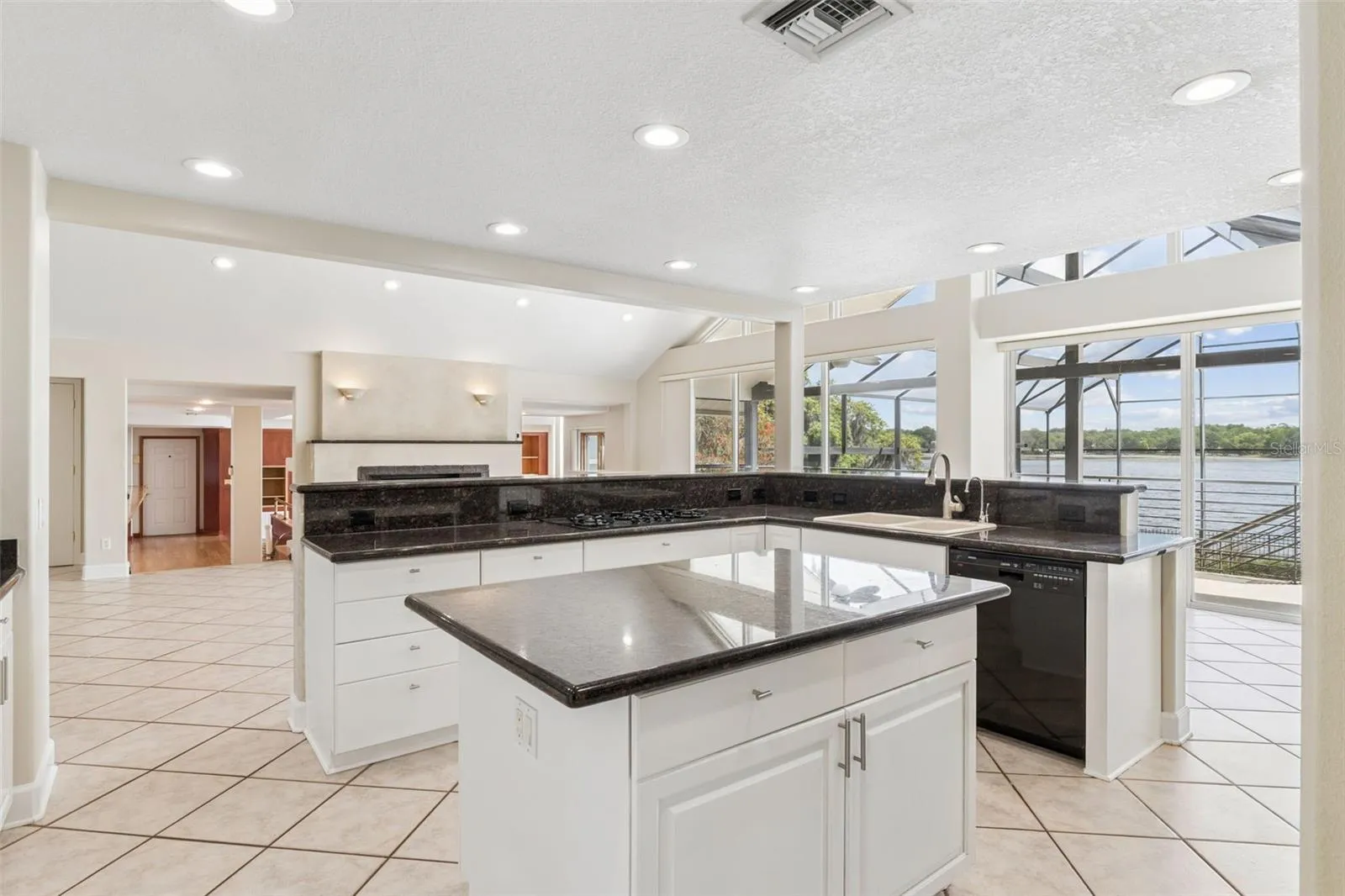 Open kitchen with center island overlooking the living room, sunken great room, and stunning lake views.