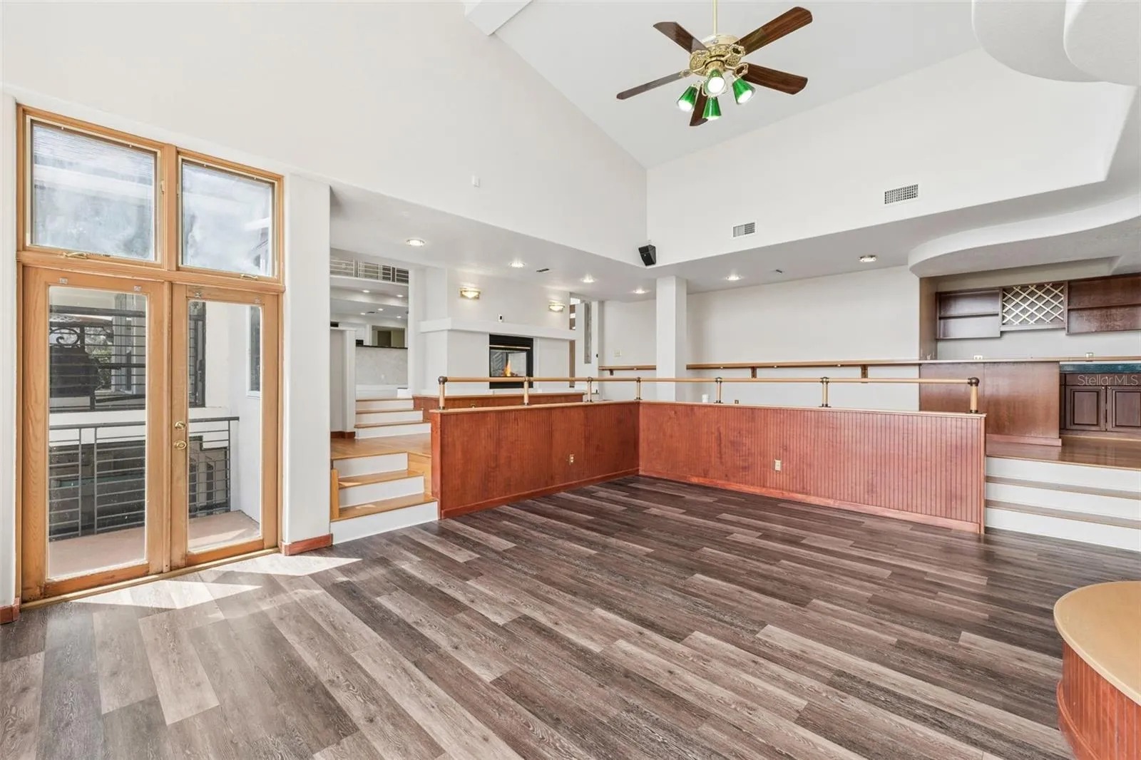 Sunken great room with soaring ceilings, lake-view windows, and French doors opening to the pool deck and lanai.