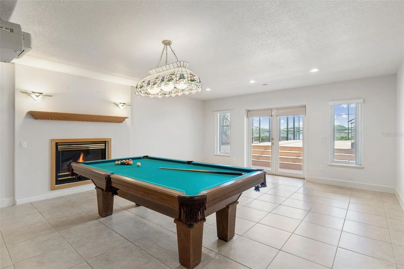 Full basement living room with fireplace and French doors opening directly to the pool deck.
