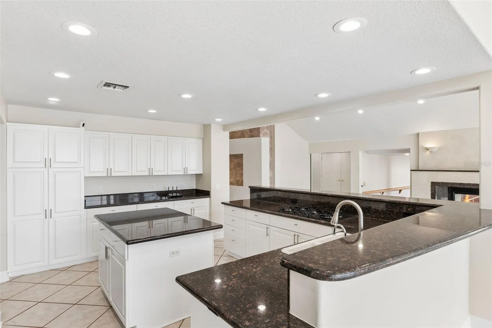 Spacious open kitchen with center island, abundant cabinetry, and views into the living room fireplace.