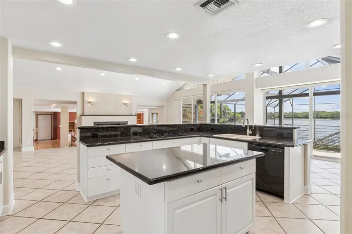 Open kitchen with center island overlooking the living room, sunken great room, and stunning lake views.
