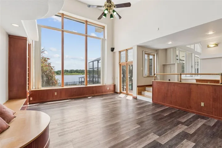 Sunken great room with soaring ceilings, lake-view windows, and French doors opening to the pool deck and lanai.