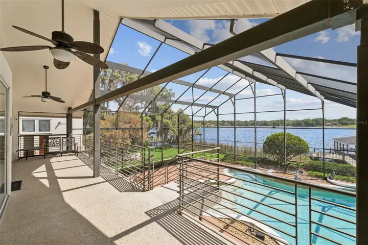 Main-level screened lanai overlooking the pool and lake, connected to the dining, kitchen, living, and great room areas.