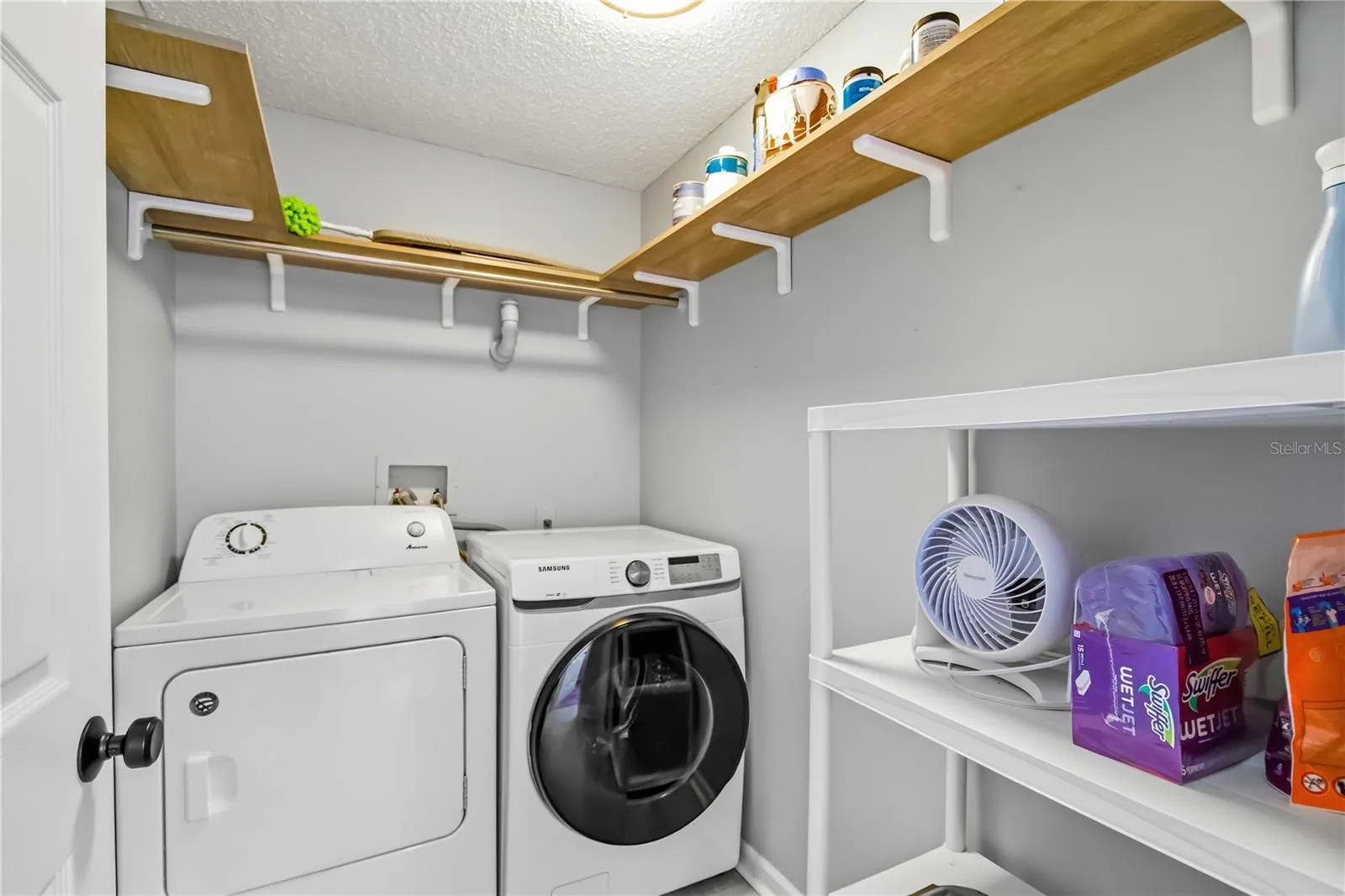 The laundry room features a full-size side-by-side washer and dryer with additional storage