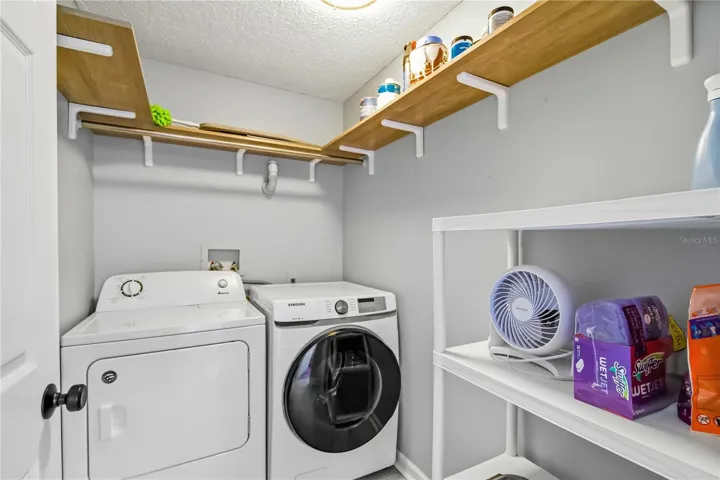 The laundry room features a full-size side-by-side washer and dryer with additional storage