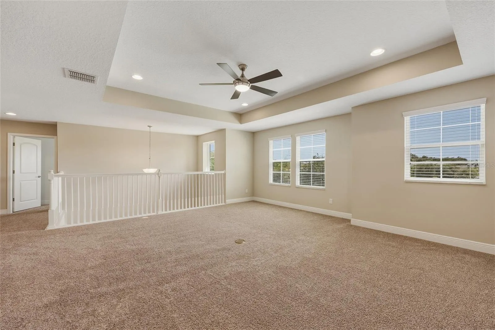 Spacious upstairs loft/bonus room with architectural tray ceiling and recessed lighting