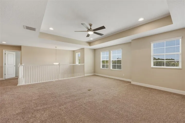 Spacious upstairs loft/bonus room with architectural tray ceiling and recessed lighting