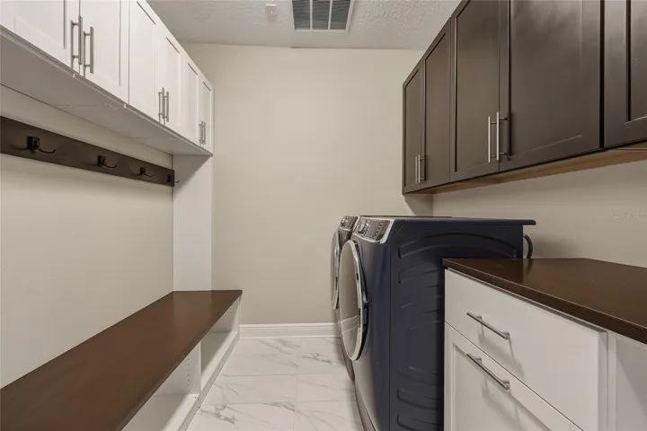 First floor laundry room with built-in cabinetry, bench, laundry hampers and drawers.