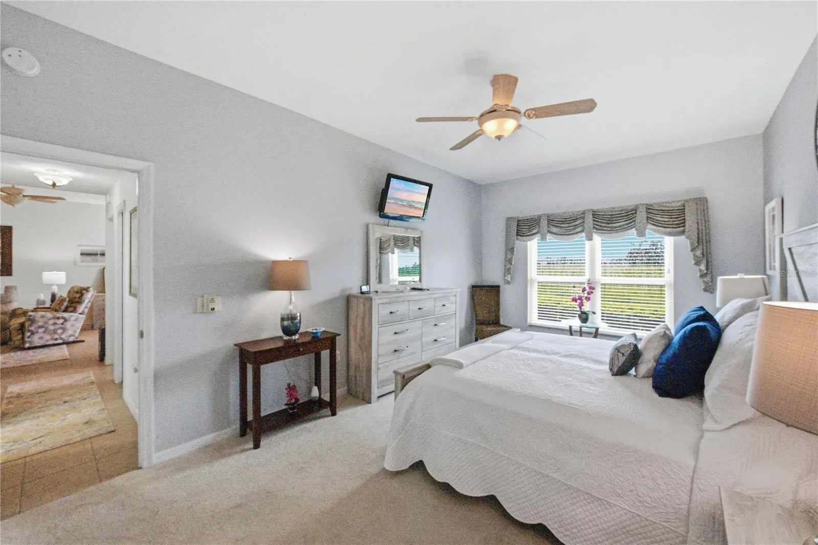The primary bedroom has quality carpeting, ceiling fan with light, quality carpeting, and designer window treatments.