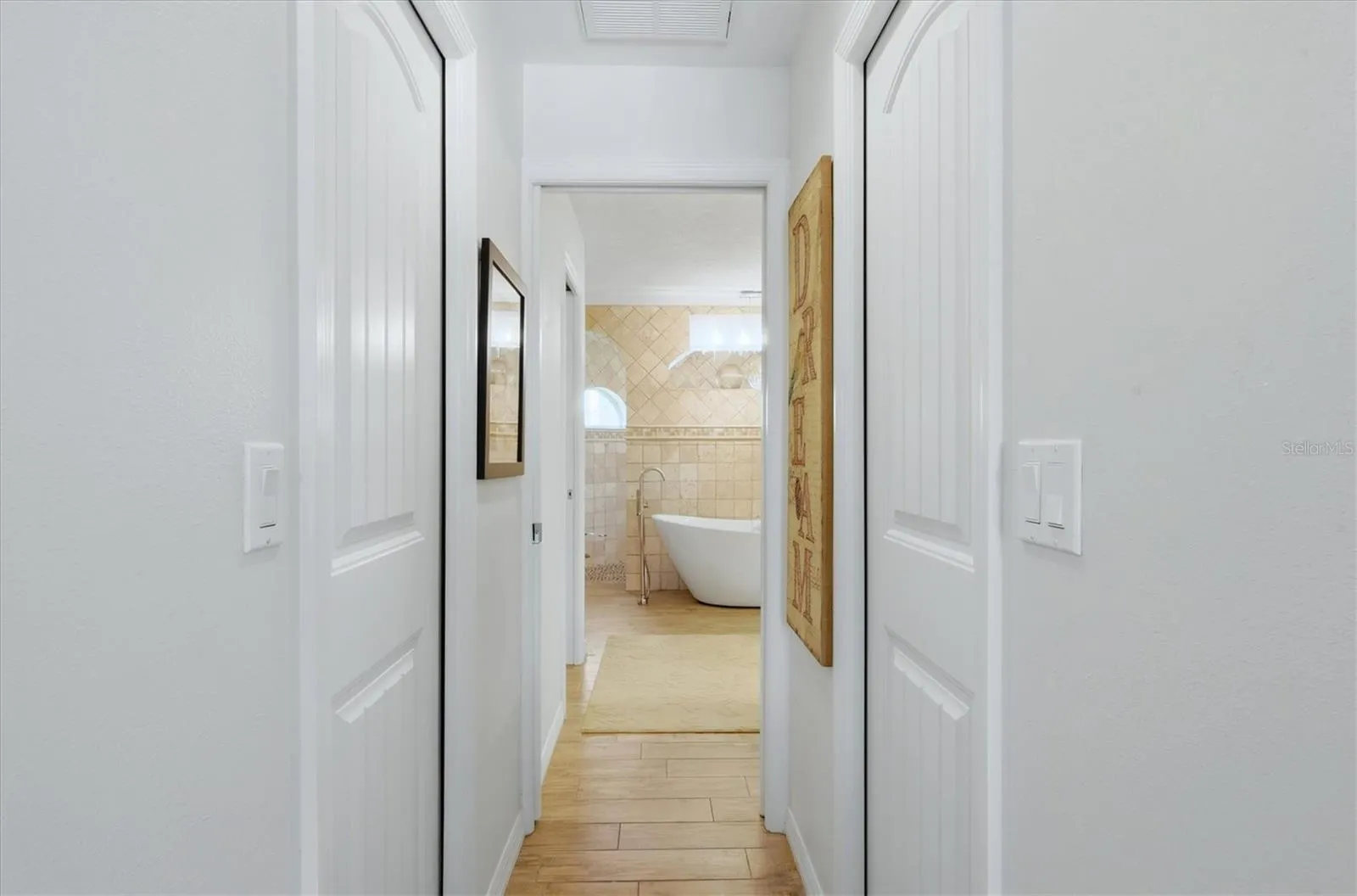 Hallway with 2 walk in closets to large primary bath