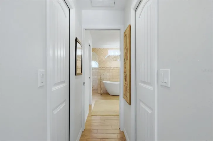 Hallway with 2 walk in closets to large primary bath