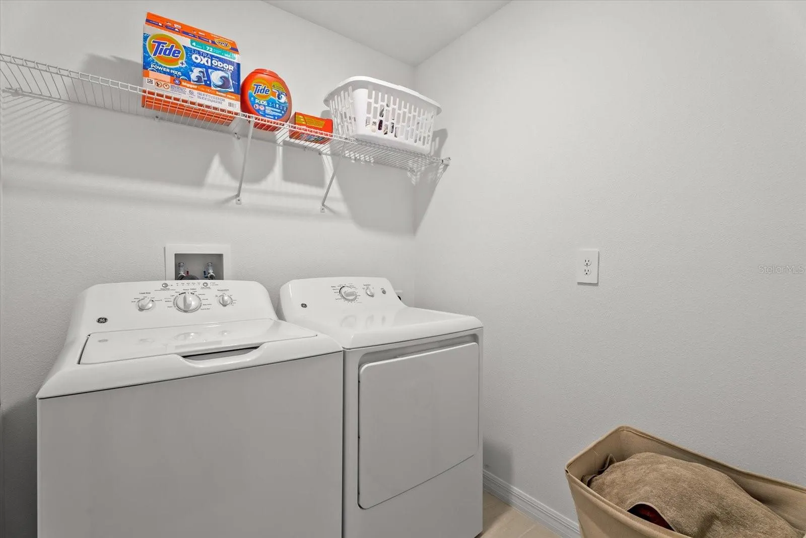 Convenient upstairs laundry room with washer, dryer, and storage shelf.