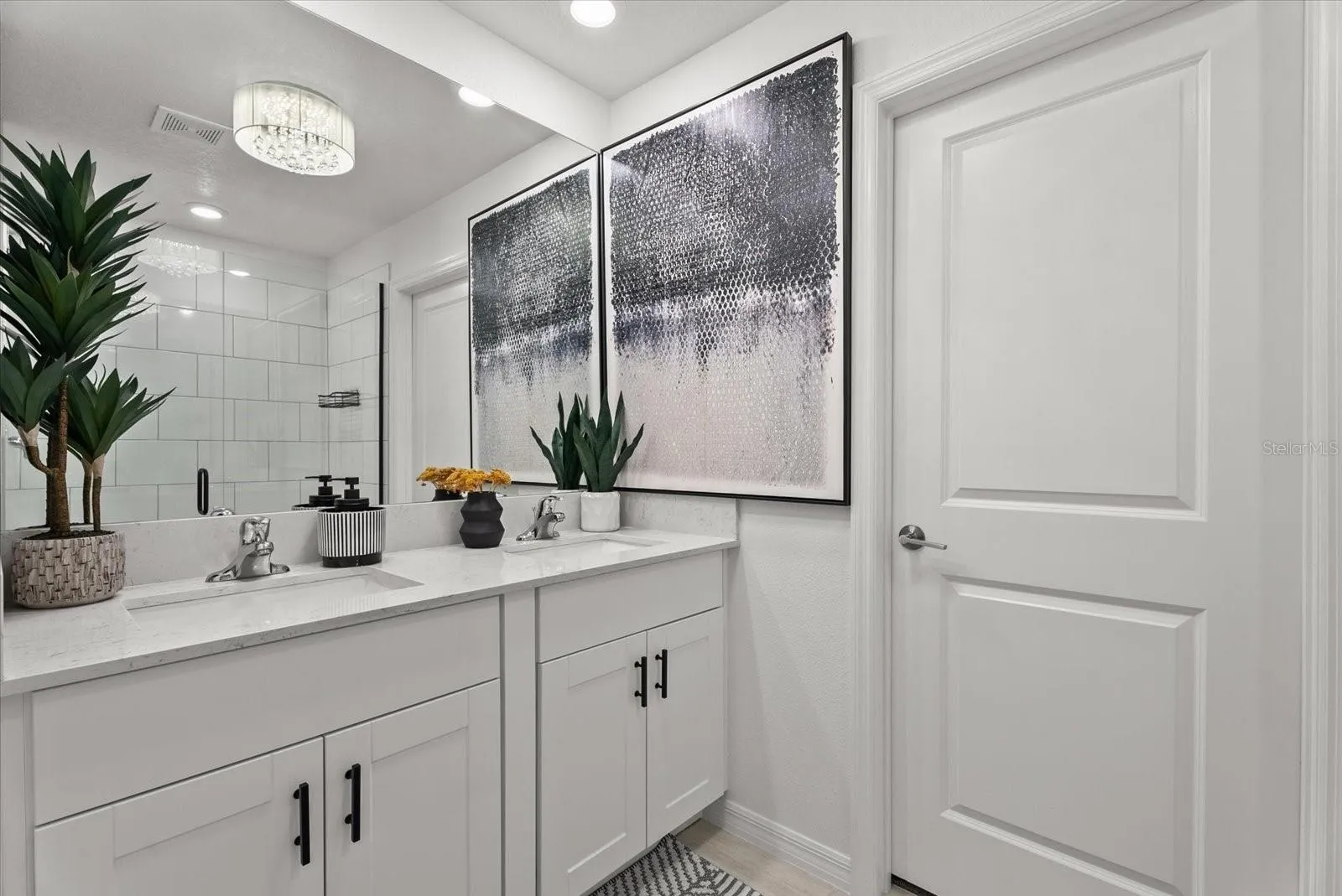 Primary bathroom featuring a double vanity, modern fixtures, and tiled shower.