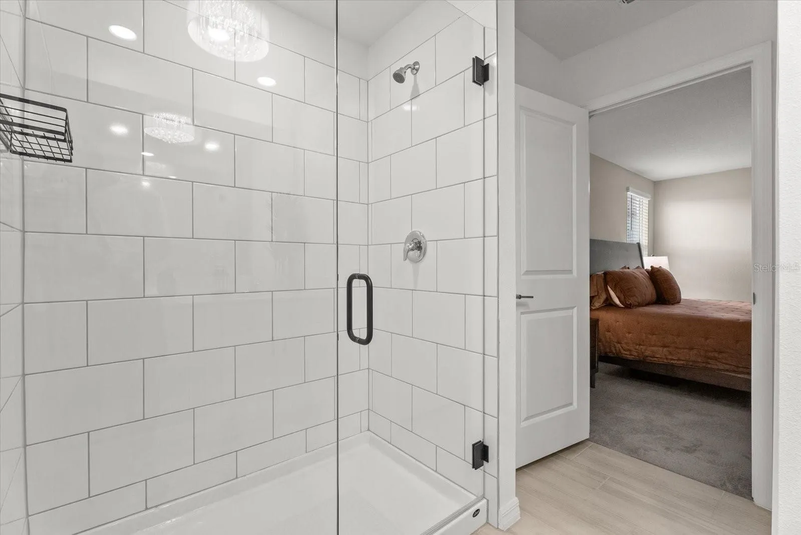 Primary bathroom featuring a tiled walk-in shower with a frameless glass door.