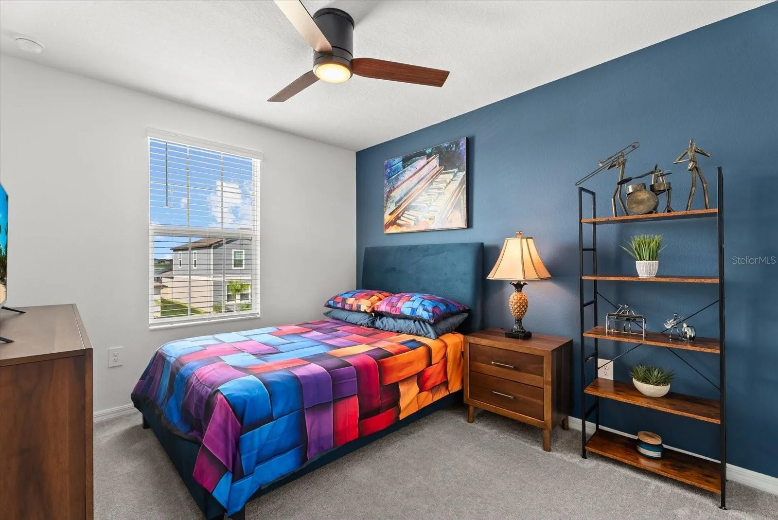 Additional bedroom featuring a ceiling fan, accent wall, and natural light.