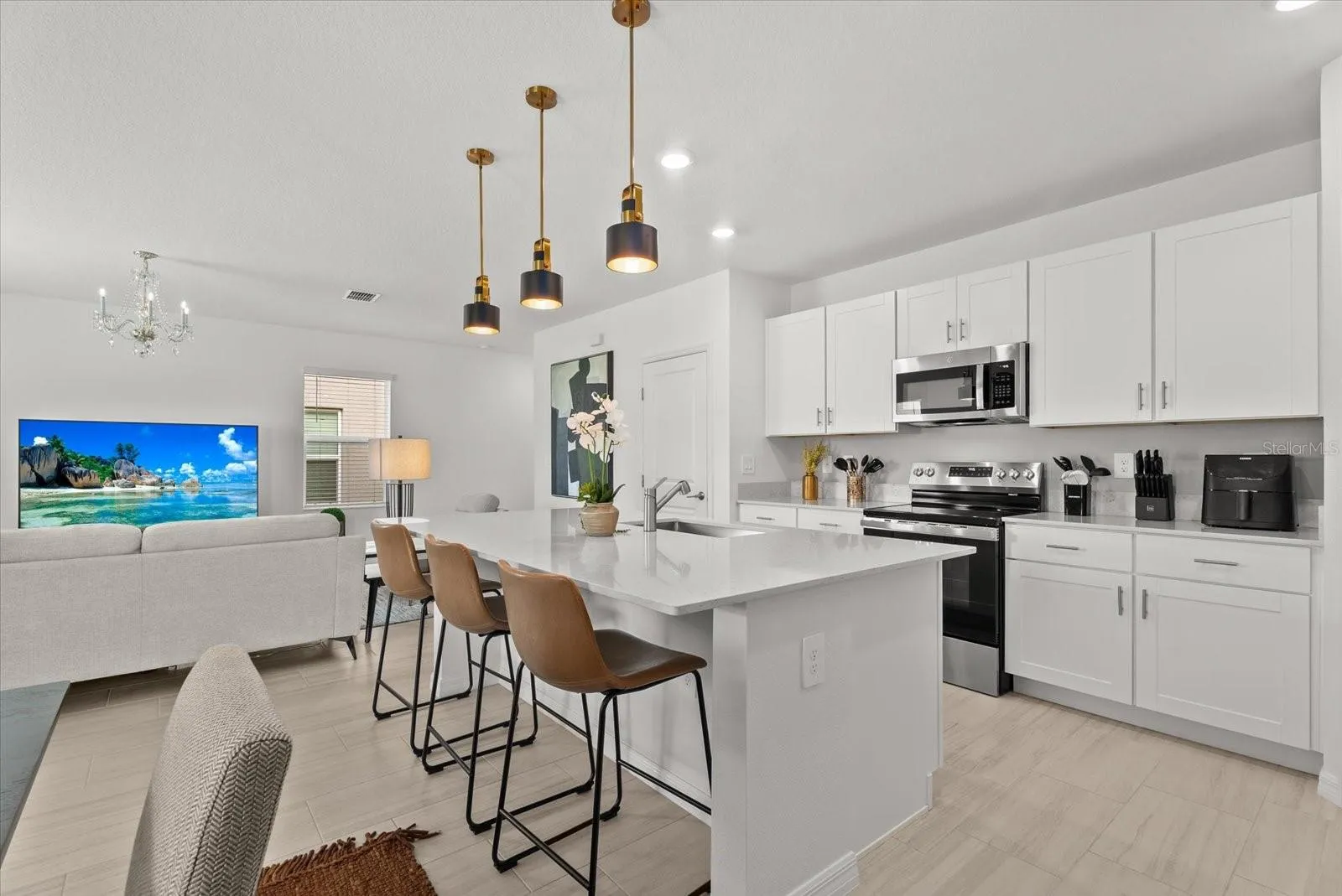 Open kitchen featuring white cabinetry, stone countertops, and stainless-steel appliances.