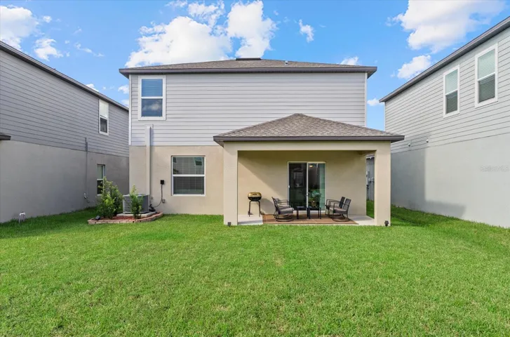 Rear exterior view showcasing the covered patio and generous lawn.