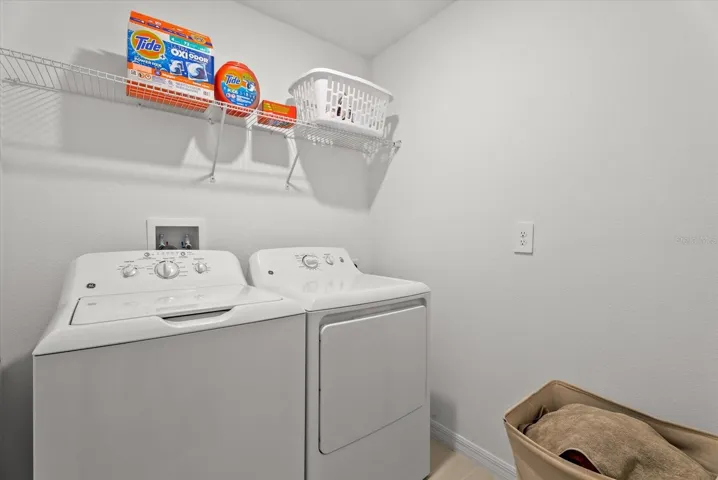 Convenient upstairs laundry room with washer, dryer, and storage shelf.