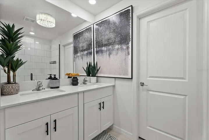 Primary bathroom featuring a double vanity, modern fixtures, and tiled shower.