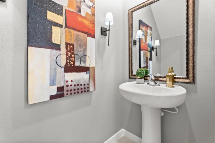 Stylish first-floor powder room with pedestal sink and framed mirror.