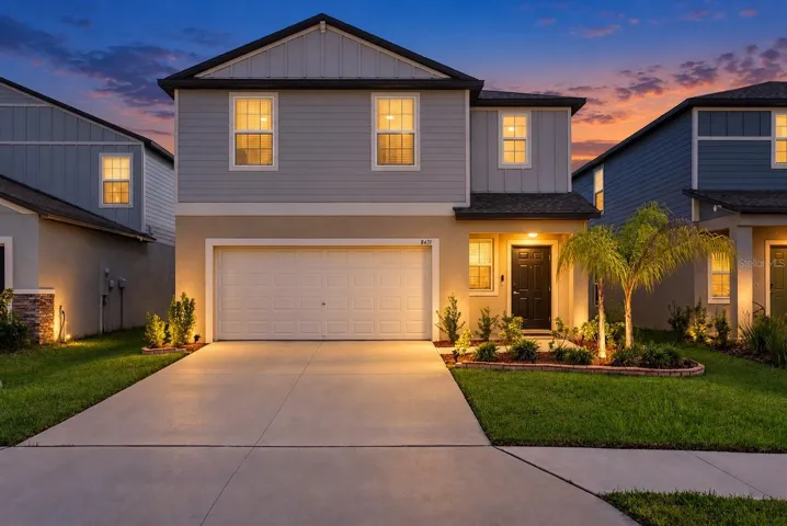 Beautiful Twilight Front Elevation with Tropical Landscaping and a Well-Maintained Lawn