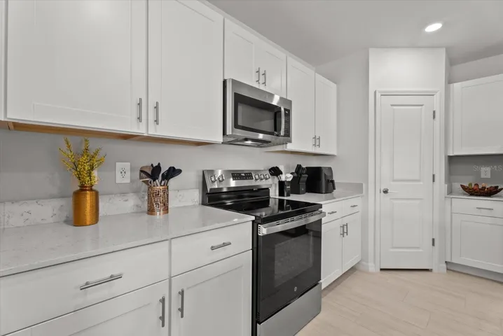 Sleek stainless-steel range and microwave surrounded by bright white cabinetry.