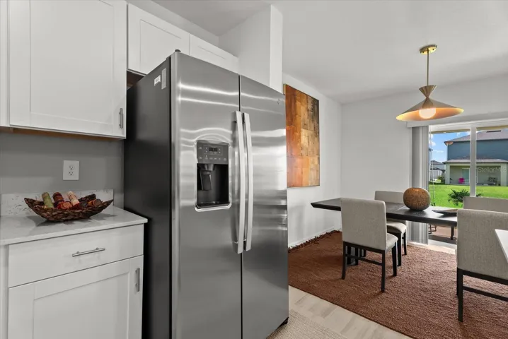 Stainless-steel refrigerator with the adjoining dining area and backyard view.