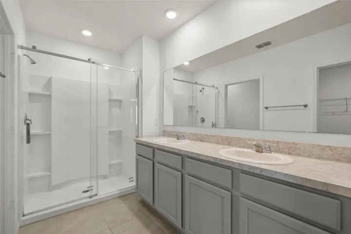 Primary bathroom featuring a spacious vanity and walk-in shower.