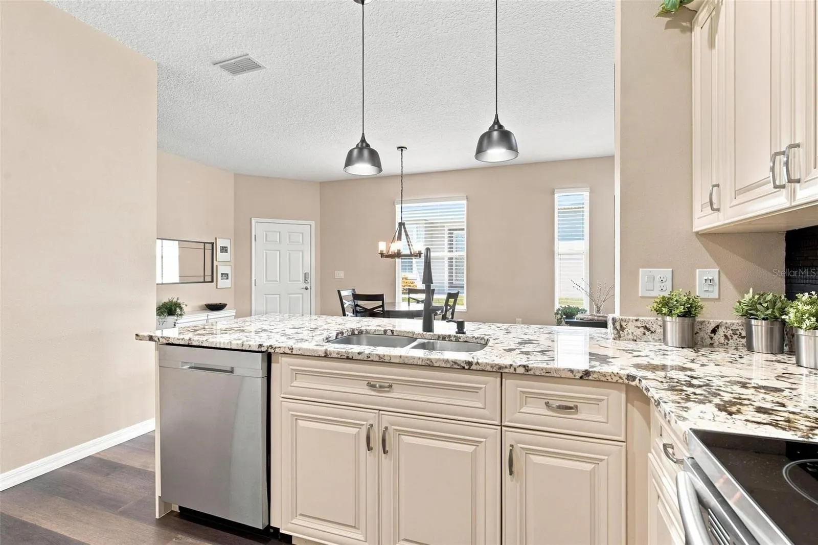 Kitchen overlooks dining and living area. Kitchen features recessed lighting, upgraded cabinets with soft close features, stainless steel appliances, backsplash, and upgraded granite countertops.