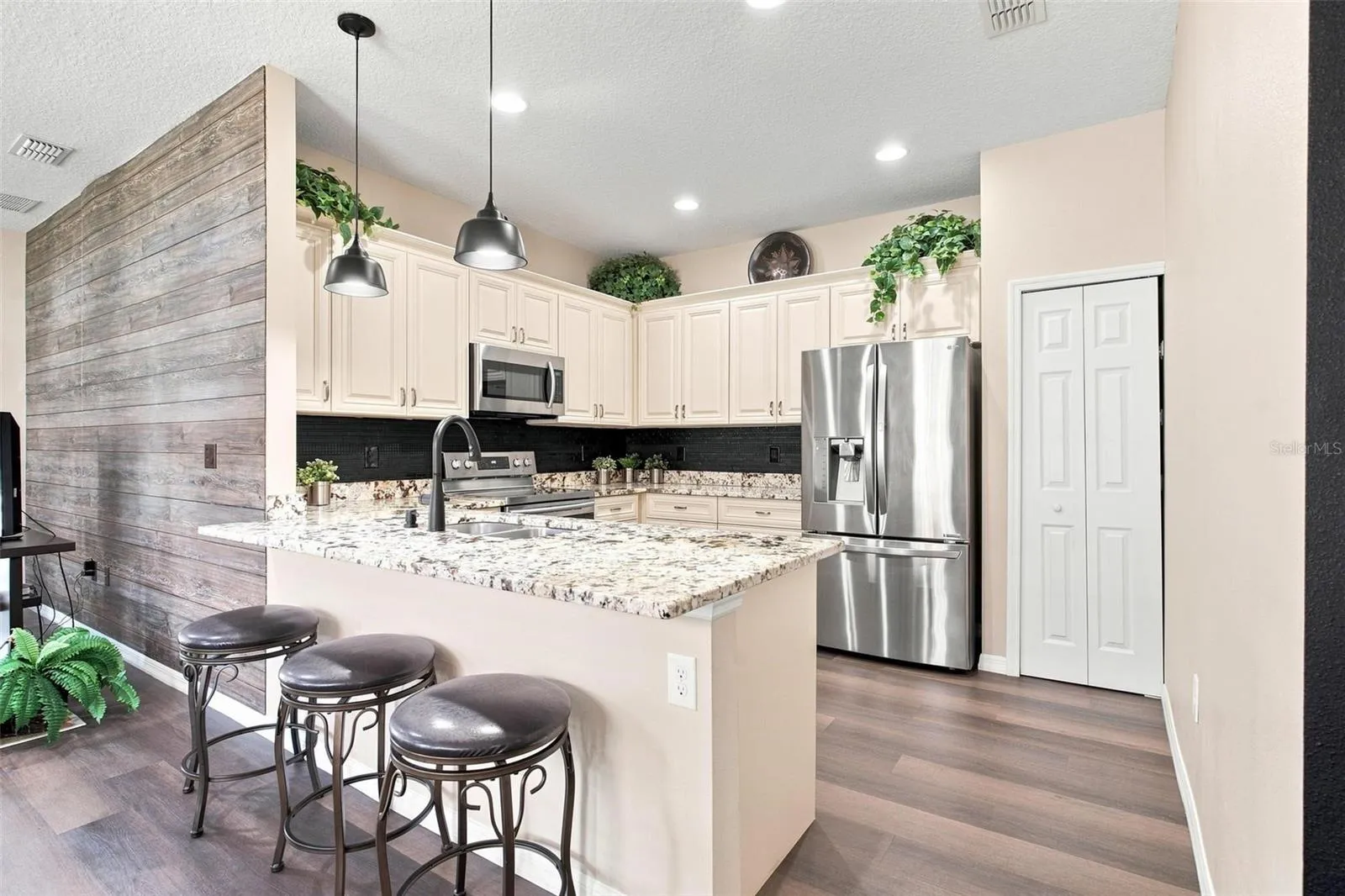Kitchen overlooks dining and living area. Kitchen features recessed lighting, upgraded cabinets with soft close features, stainless steel appliances, backsplash, and upgraded granite countertops.