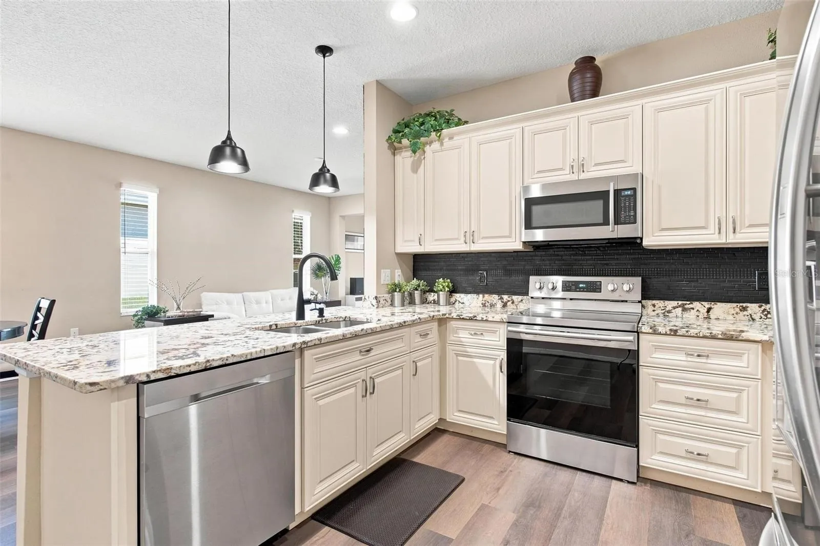 Kitchen overlooks dining and living area. Kitchen features recessed lighting, upgraded cabinets with soft close features, stainless steel appliances, backsplash, and upgraded granite countertops.
