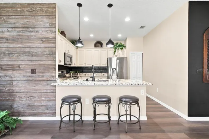 Kitchen overlooks dining and living area. Kitchen features recessed lighting, upgraded cabinets with soft close features, stainless steel appliances, backsplash, and upgraded granite countertops.