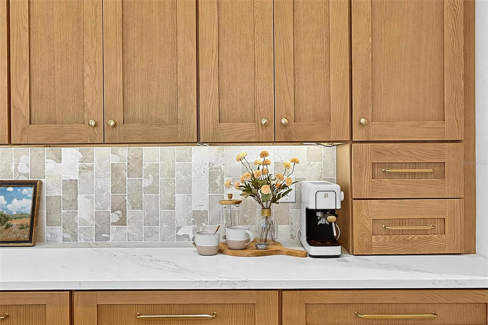 Full wall of Custom Wood soft close cabinets with under-mount lighting against the stunning tile and quartz countertops