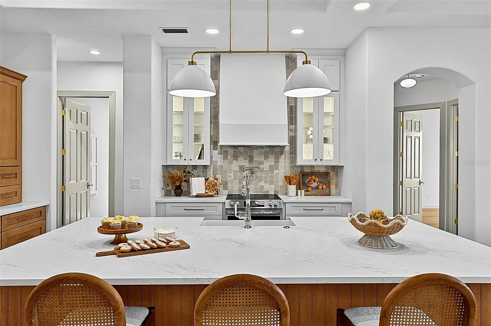 Elegant Centerpiece Kitchen Island with crafted wall of tile and lighted window cabinets