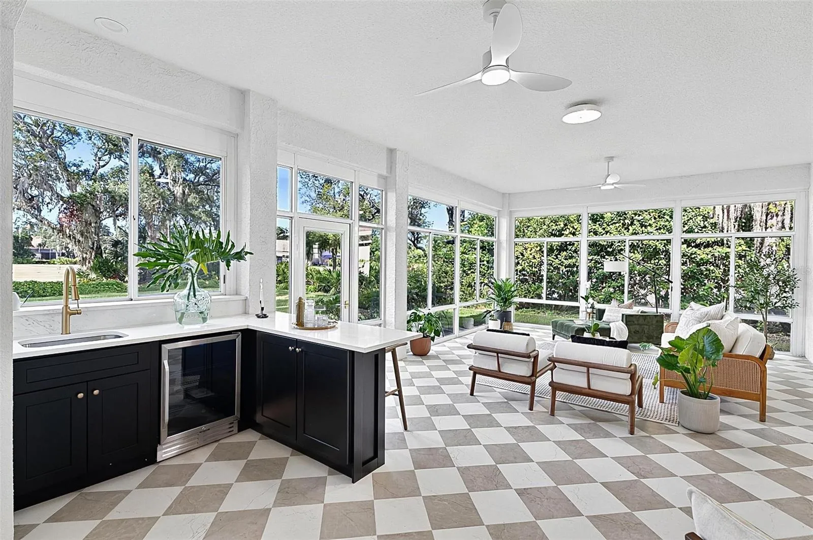 Custom wet bar with beverage refrigerator and quartz countertop in the solarium with wall to wall enclosed screen window for a view of nature at its best. Room is aired