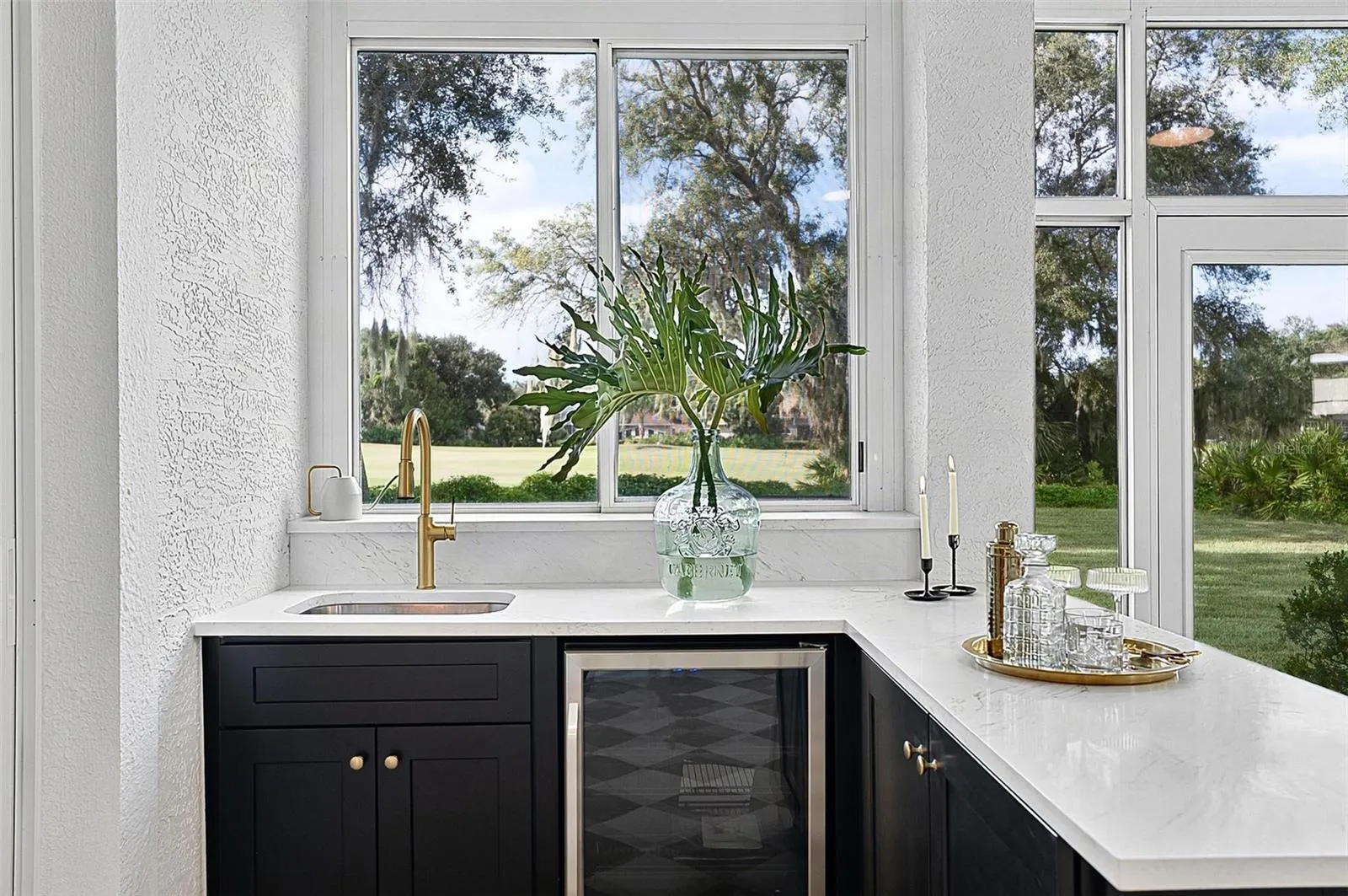 Custom wet bar with beverage refrigerator and quartz countertop in the solarium