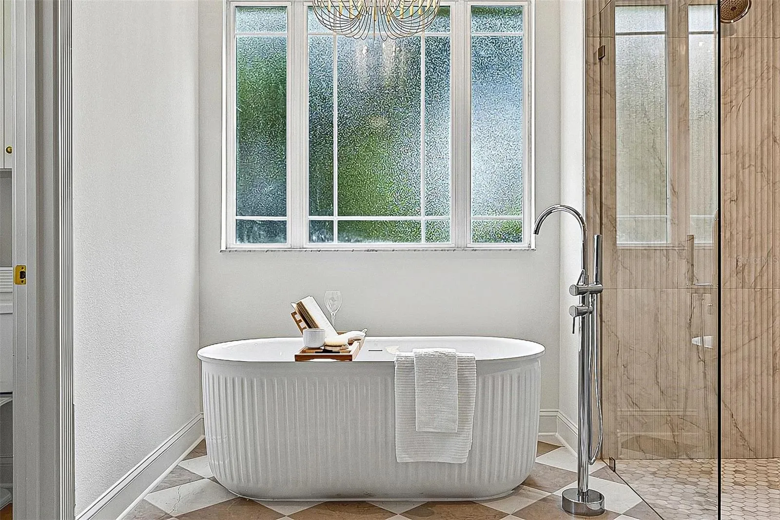 Obsure Large window brings in soft lighting into the free standing tub and tiled stand up shower