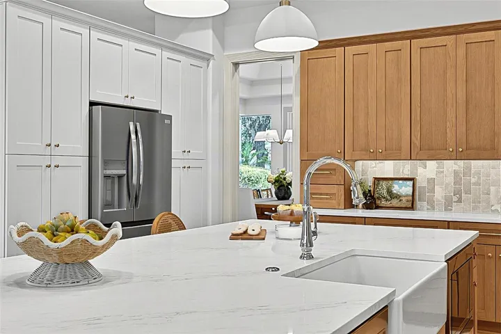 Kitchen Island with farm sink, showing refrigerator with wall of pantry cabinets