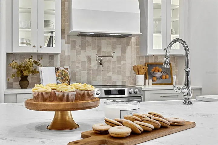 Elegant Centerpiece Kitchen Island with crafted wall of tile and lighted window cabinets