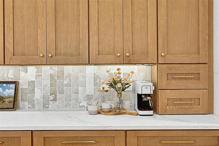 Full wall of Custom Wood soft close cabinets with under-mount lighting against the stunning tile and quartz countertops