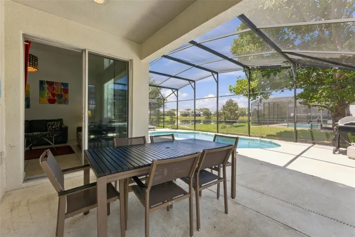 Covered patio overlooking the screened-in sparkling pool and pond.