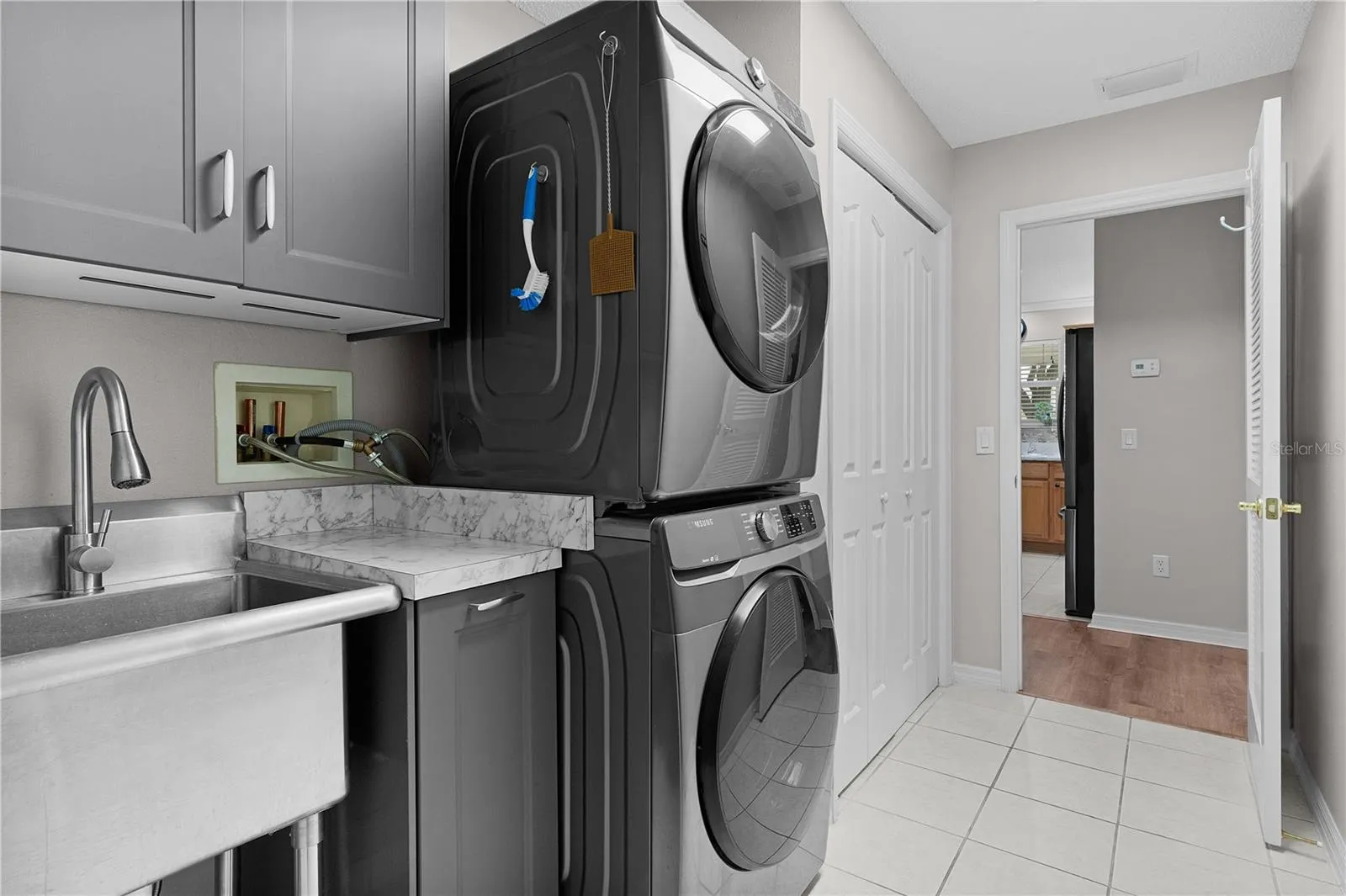 Laundry room with lots of cabinetry, mop sink &amp; stackable washer/dryer