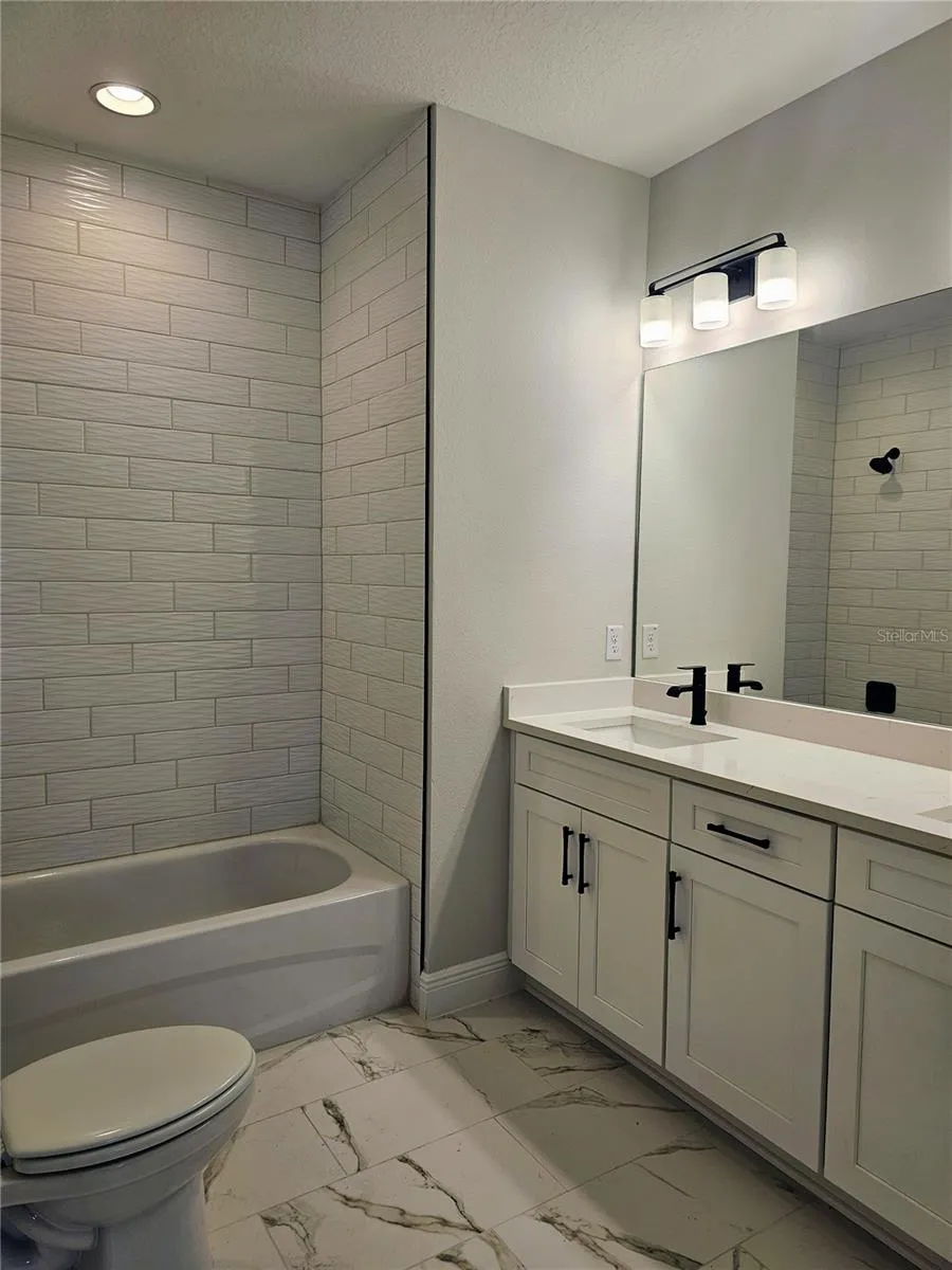 guest bathroom with double sinks, tub and shower